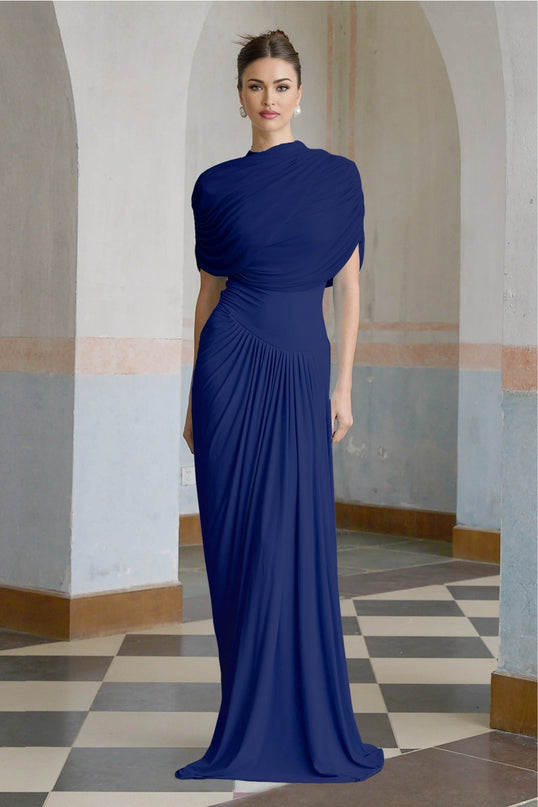 A navy blue long maxi dress with an asymmetric design and pleated details worn by a model standing against a plain background