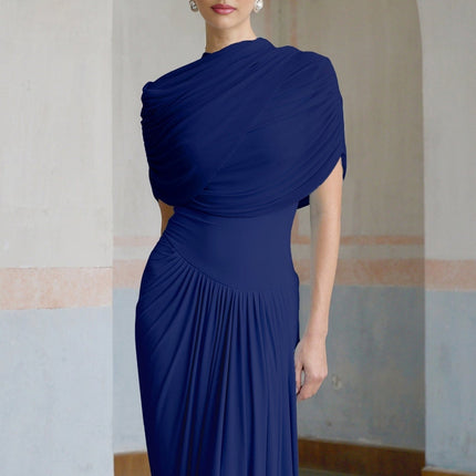 A navy blue maxi dress with an asymmetric hemline and pleated details worn by a model standing against a plain background