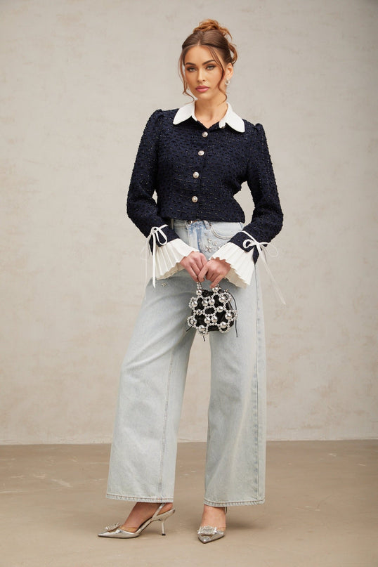 A navy blue tweed jacket with panels featuring a structured silhouette and classic tailoring details