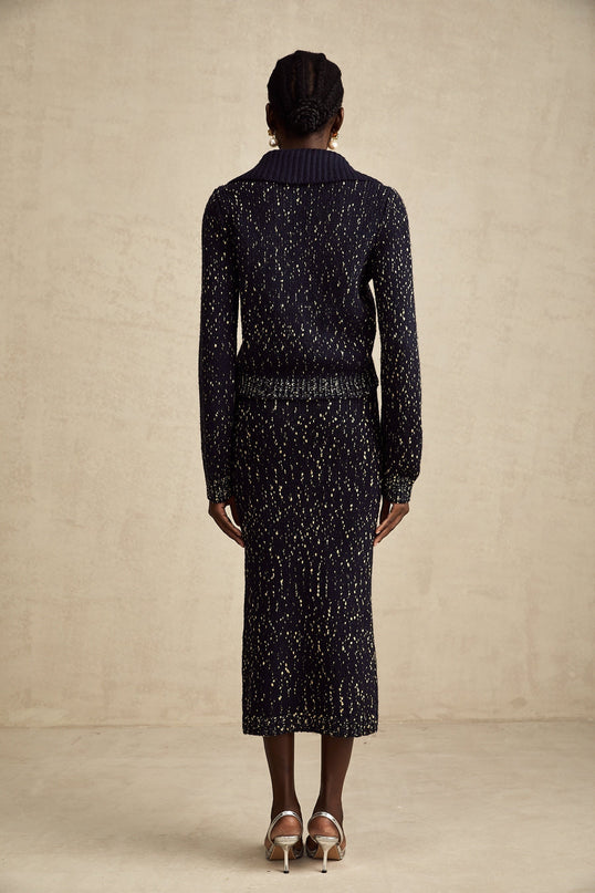A navy blue twopiece outfit consisting of a crochetknit jacket and matching skirt called Claudine The set features intricate crochet patterns throughout both pieces creating an elegant and textured appearance