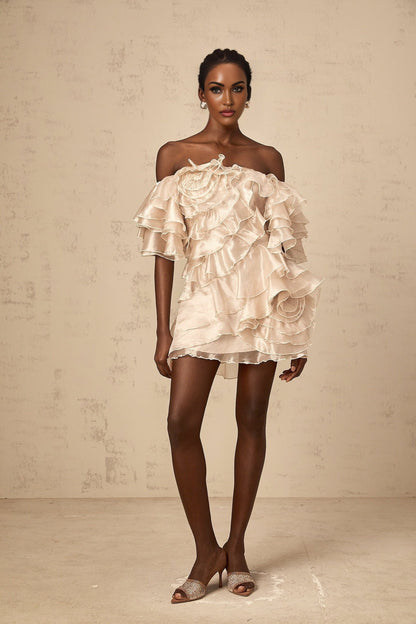 A neutral colored mini dress with an asymmetric design featuring a cerise flounce detail
