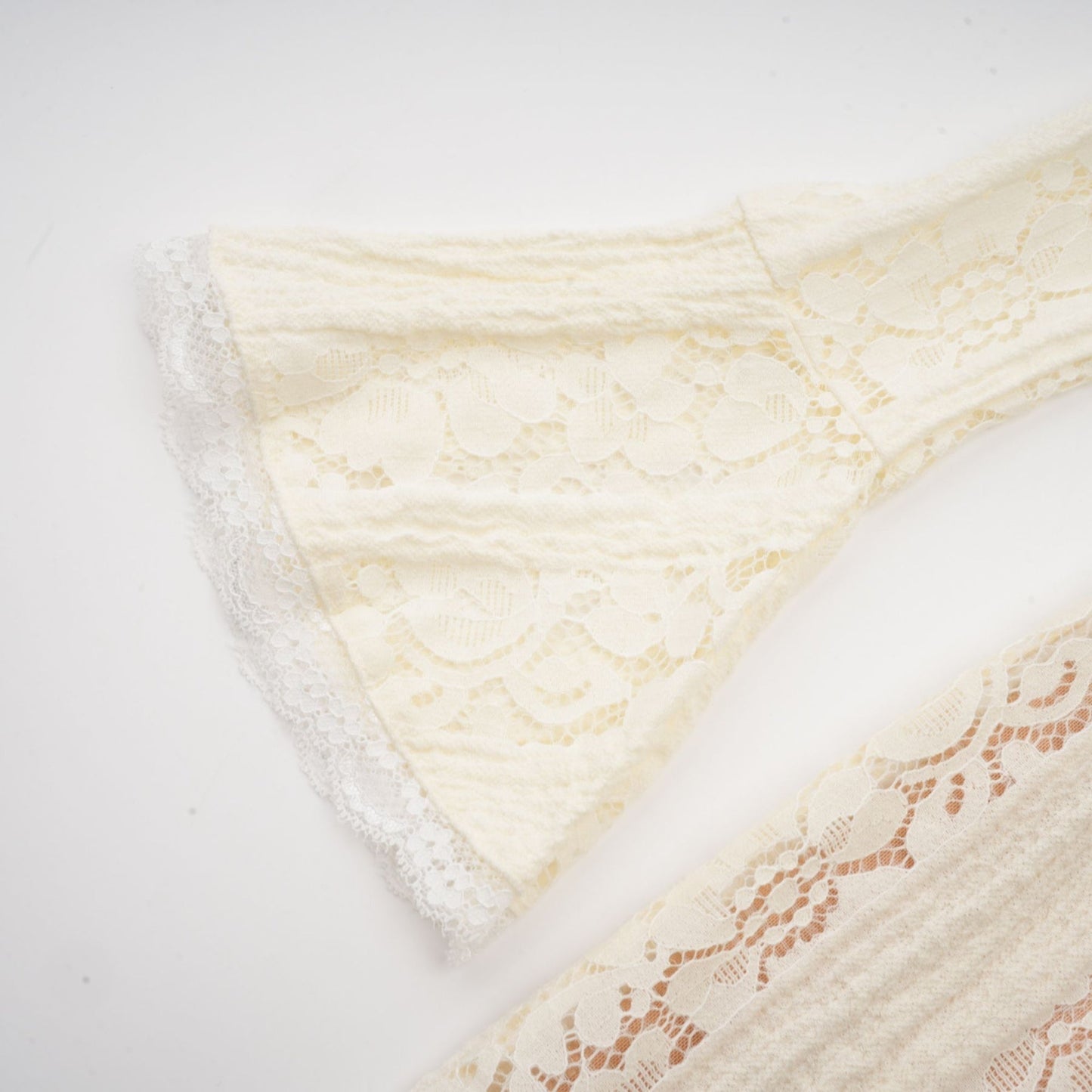 A neutral colored mini dress with floral lace pattern and flared cuffs called Emeline