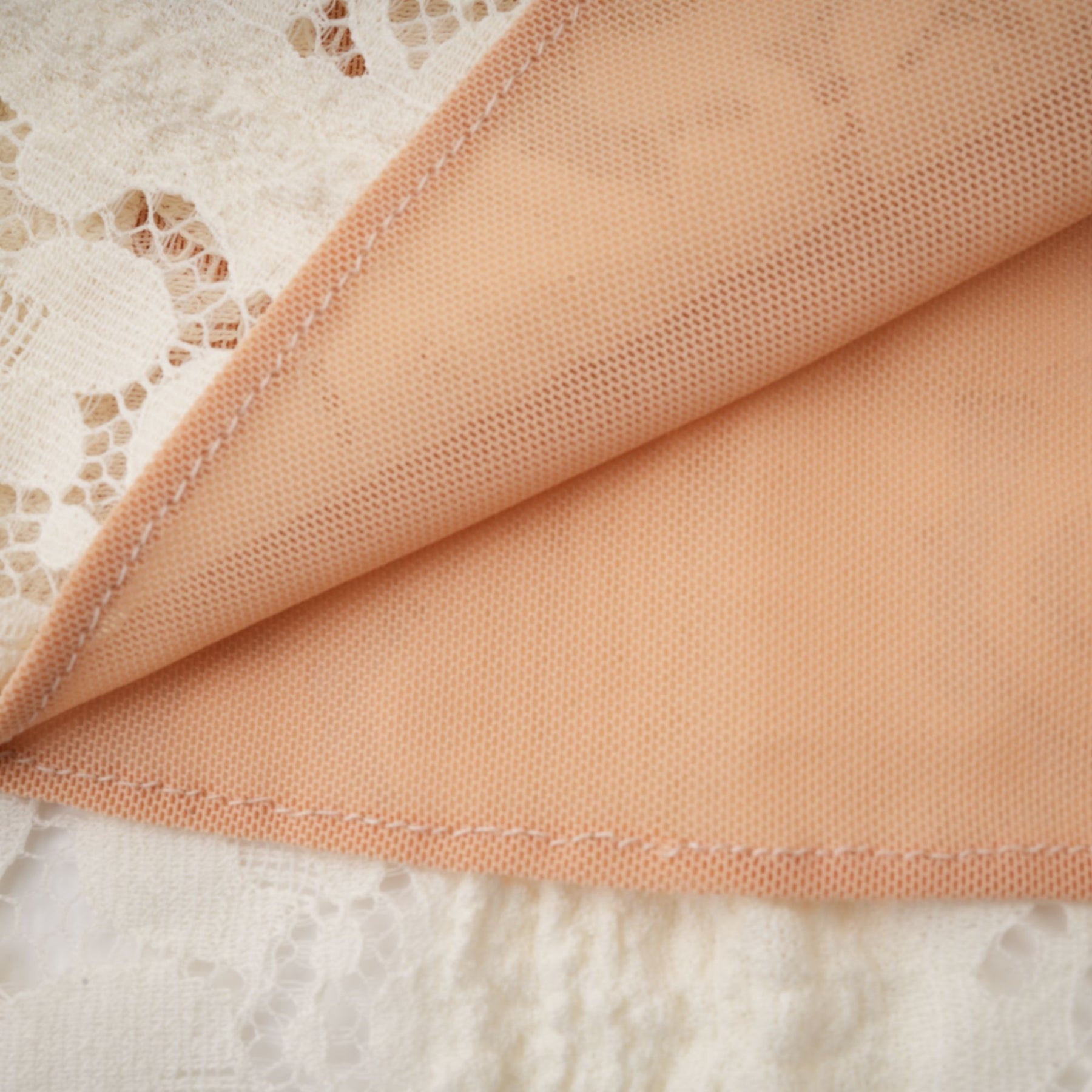 A neutral colored mini dress with floral lace pattern and flared cuffs called Emeline