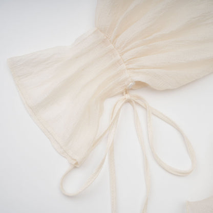 A neutral colored mini dress with tiered skirt and floral applique details called Zephyrine