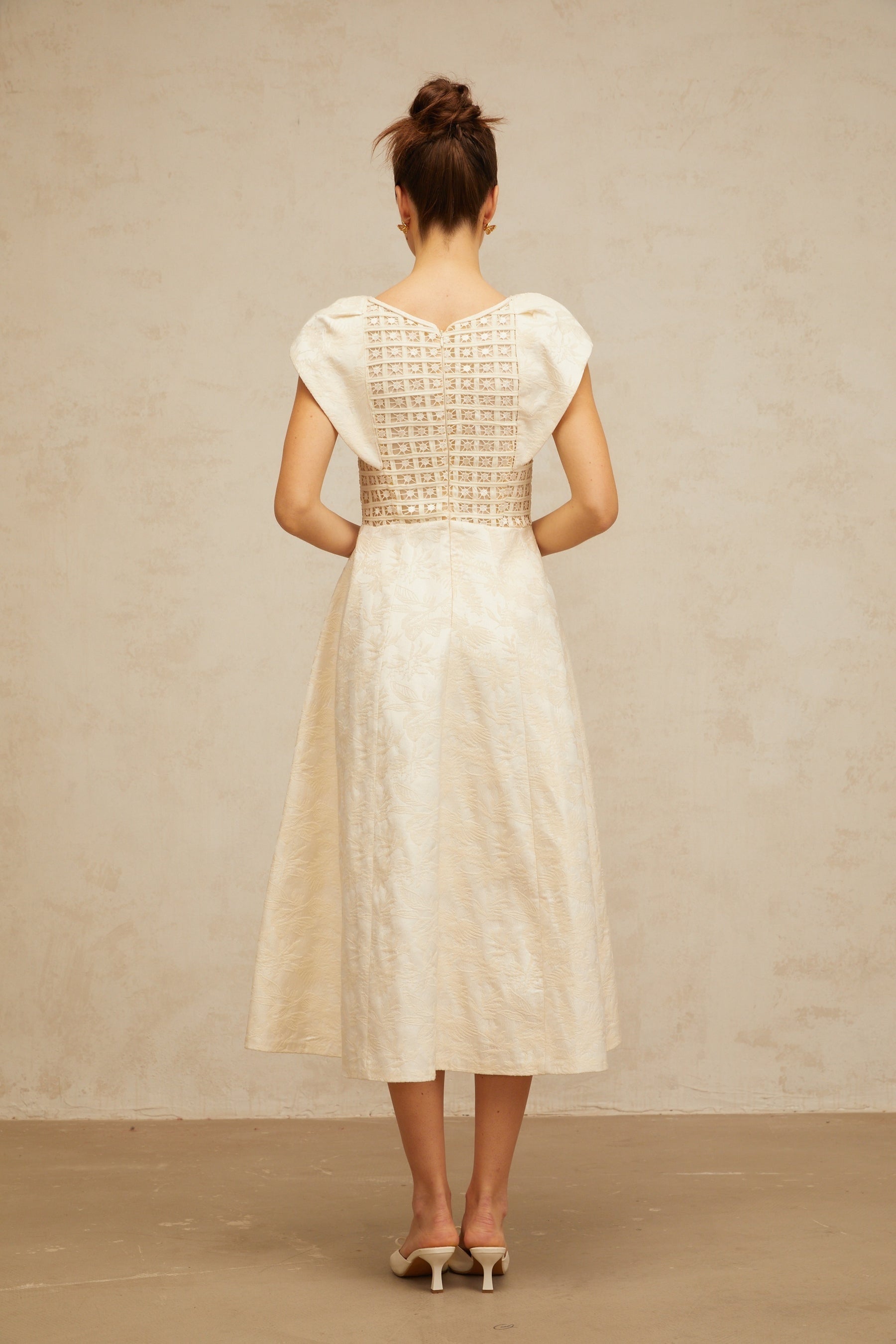A neutralcolored midi dress with floral embroidery and embellishments featuring the Xenia brand design