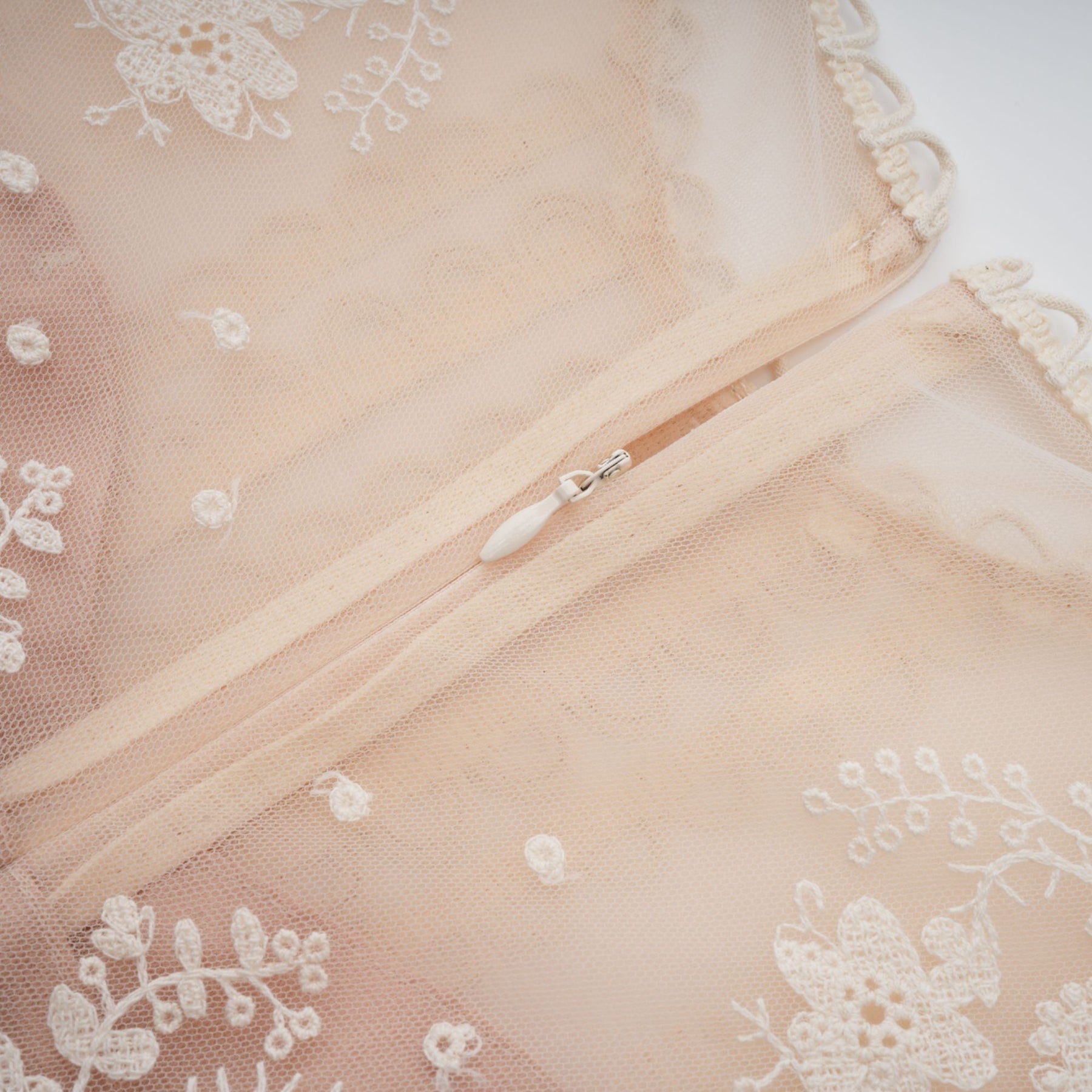 A neutralcolored midi dress with floral embroidery and lace details featuring a delicate fleur pattern