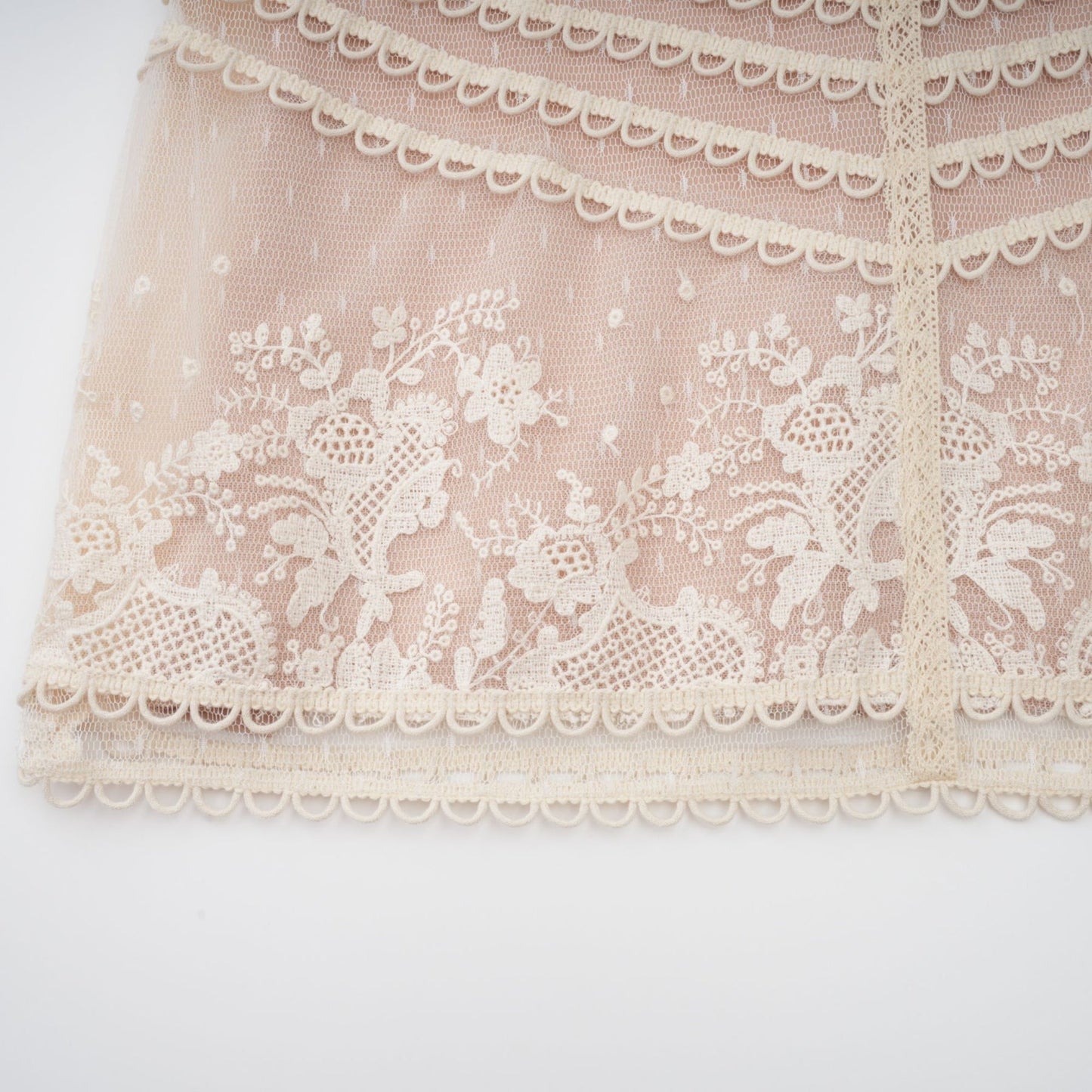 A neutralcolored midi dress with floral embroidery and lace details featuring a delicate fleur pattern