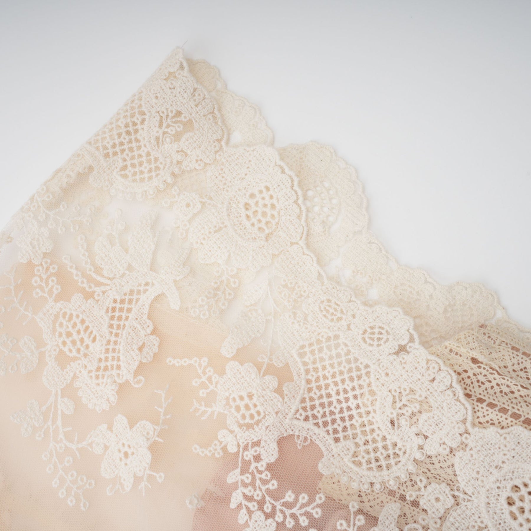 A neutralcolored midi dress with floral embroidery and lace details featuring a delicate fleur pattern