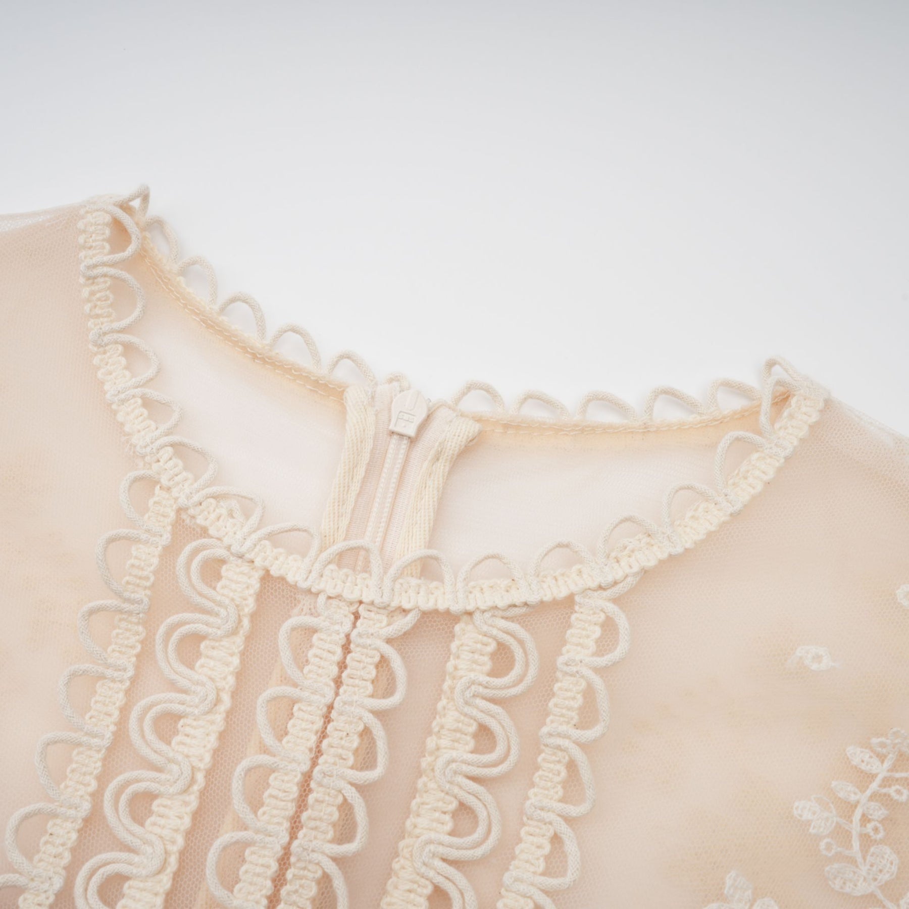 A neutralcolored midi dress with floral embroidery and lace details featuring a delicate fleur pattern
