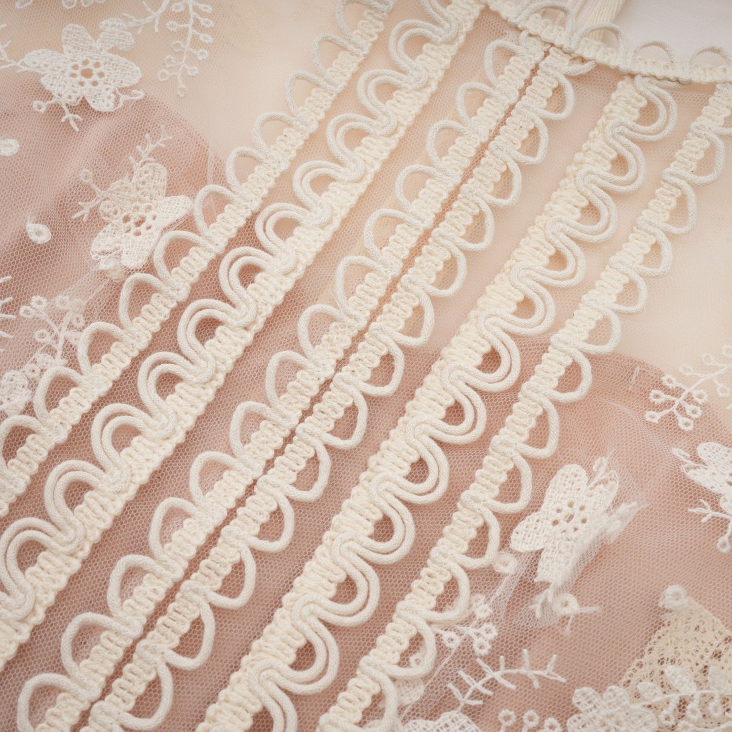 A neutralcolored midi dress with floral embroidery and lace details featuring a delicate fleur pattern