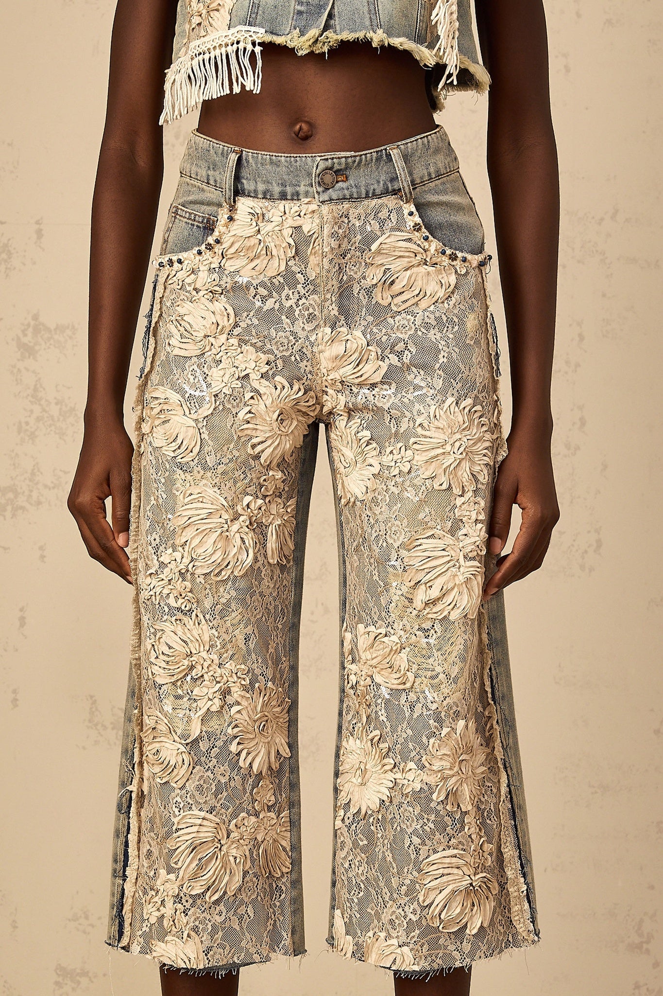 A pair of blue denim jeans with floral lace panels featuring an amaryllis flower design