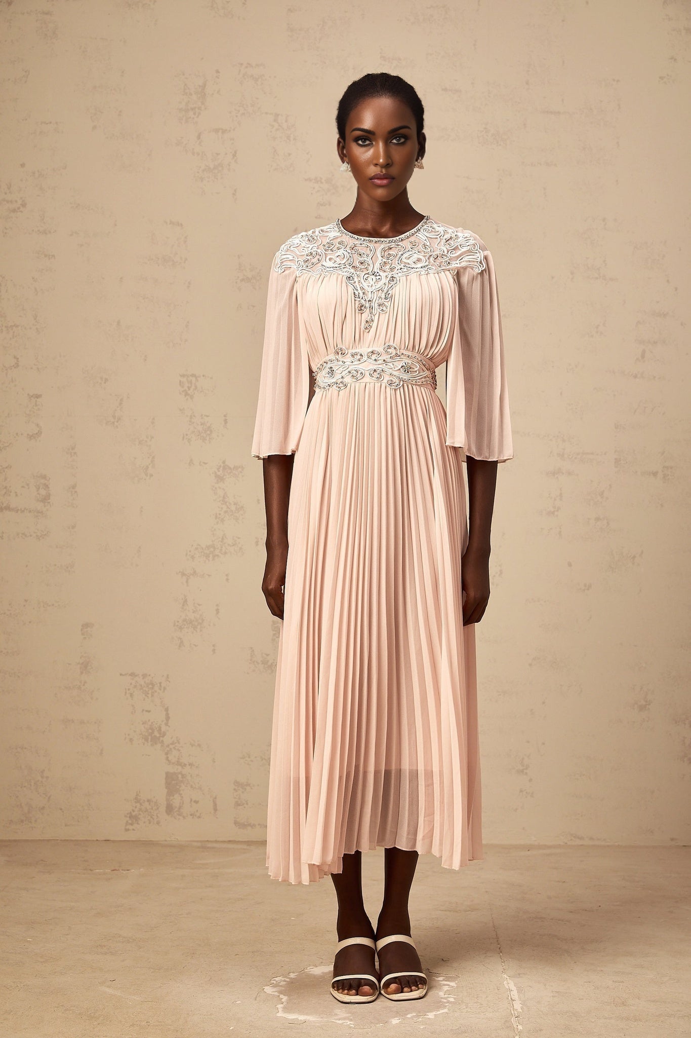 A pink crystal embellished midi dress with full pleats and a flowing silhouette