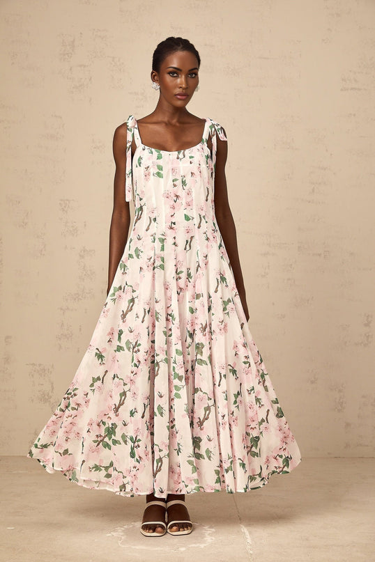 A pink floral print maxi dress with tied straps and a long flowing skirt