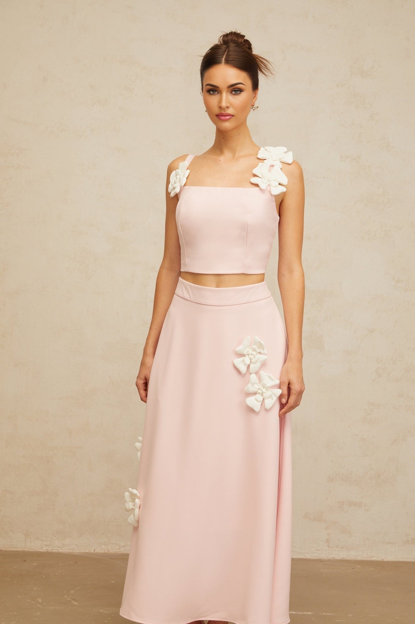 A pink matching set consisting of a top and skirt adorned with floral appliques