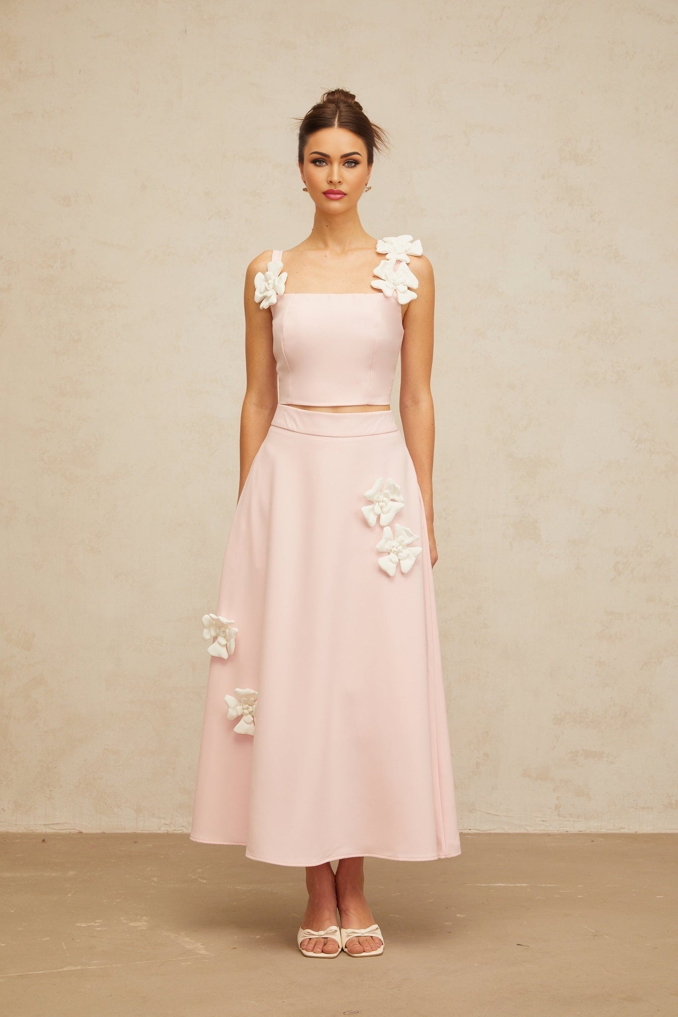 A pink matching set consisting of a top and skirt decorated with floral appliques