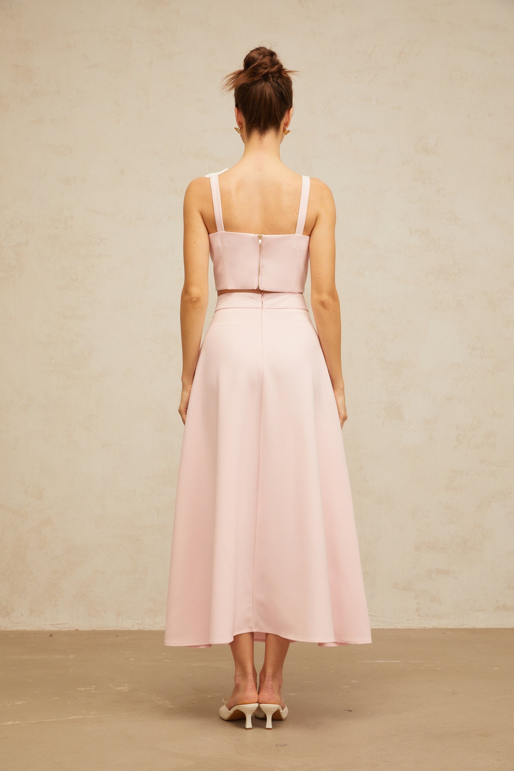 A pink matching set consisting of a top and skirt featuring floral applique details The top is sleeveless with a fitted silhouette The skirt has a slim fit and falls to midi length Both pieces are adorned with delicate pink floral embellishments