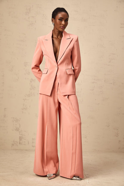 A pink matching set featuring a blazer and trousers with embroidery details and cutout design The blazer has an open front while the trousers are tailored Both pieces have decorative embroidery and strategic cutouts for a stylish look