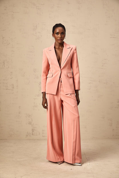 A pink matching set featuring a blazer and trousers with embroidery details and cutout designs The blazer has long sleeves and the trousers are full length Both pieces have a tailored fit and coordinating embroidery patterns