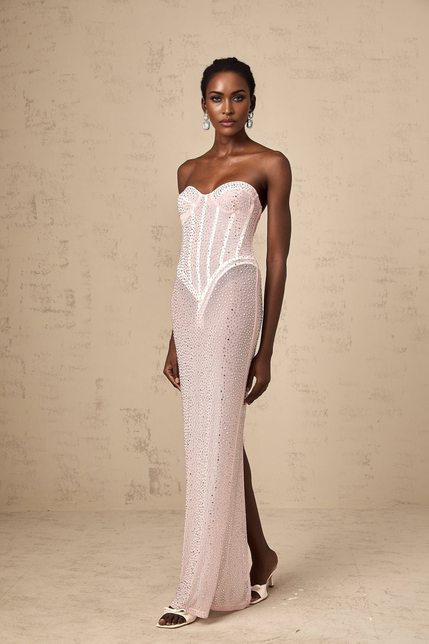 A pink maxi dress with rhinestone embellishments and a semi sheer design featuring a long flowing silhouette