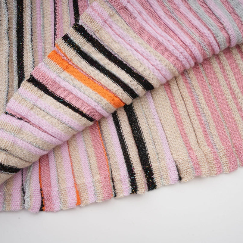 A pink metallic midi dress with pleats named Mathilde featuring a shimmering fabric and a flowy silhouette that falls to mid calf length