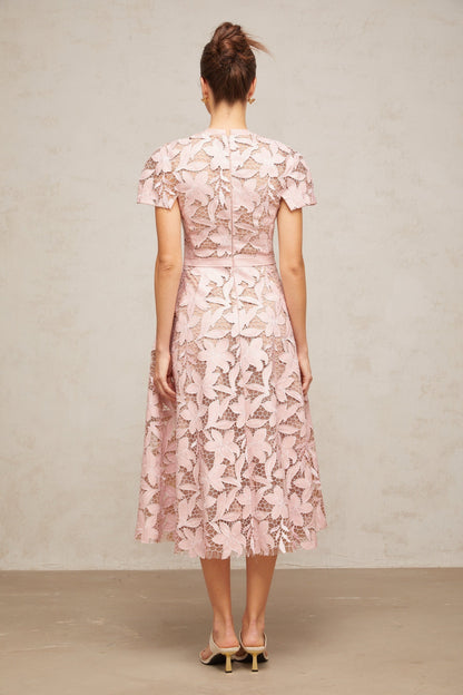 A pink midi dress made of delicate guipure lace featuring intricate floral patterns and a feminine silhouette