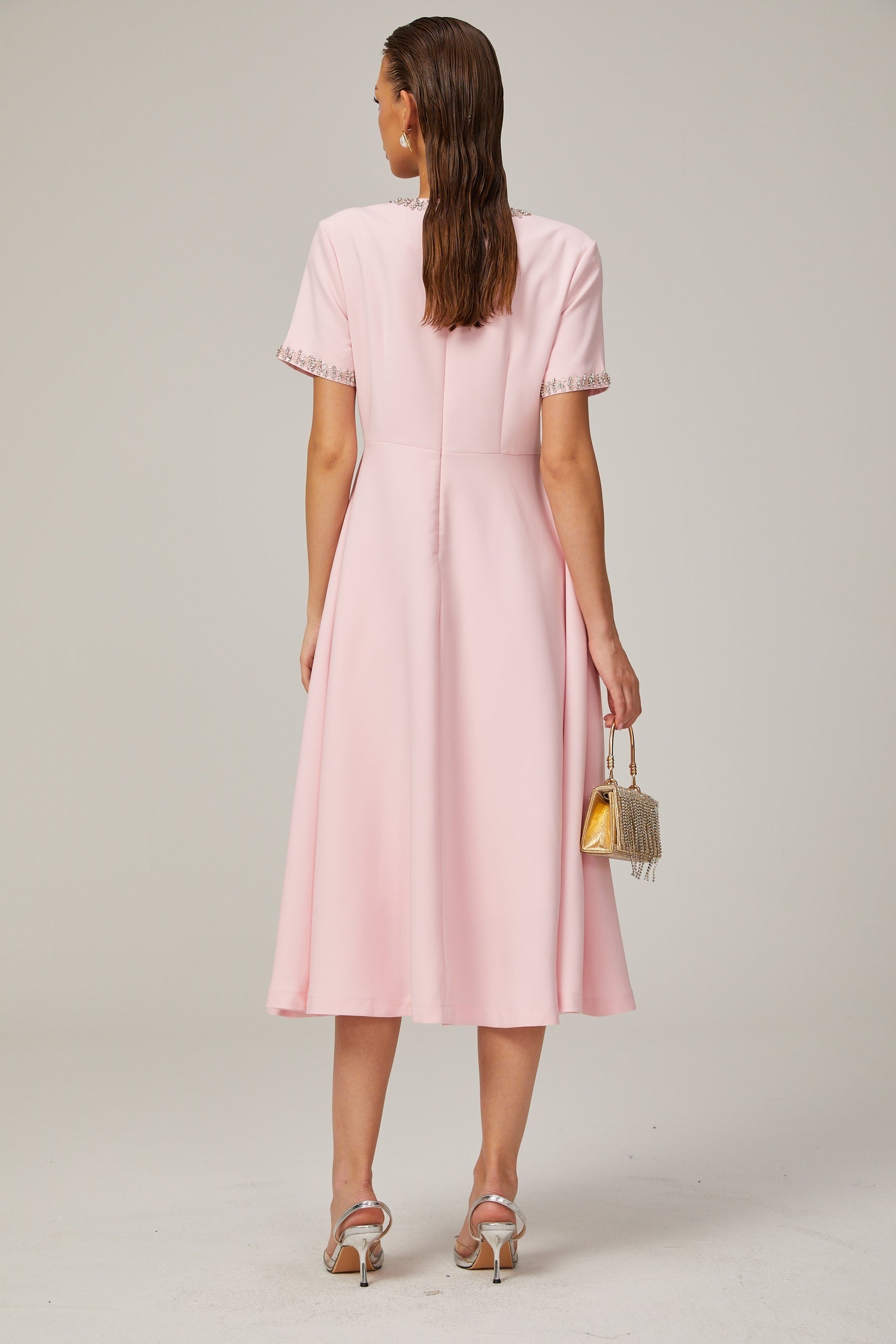 A pink midi dress with a crystalaccented bow and a Cassiopeiainspired design