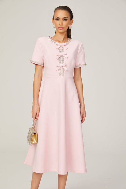 A pink midi dress with a crystalaccented bow detail and a Cassiopeia inspired design