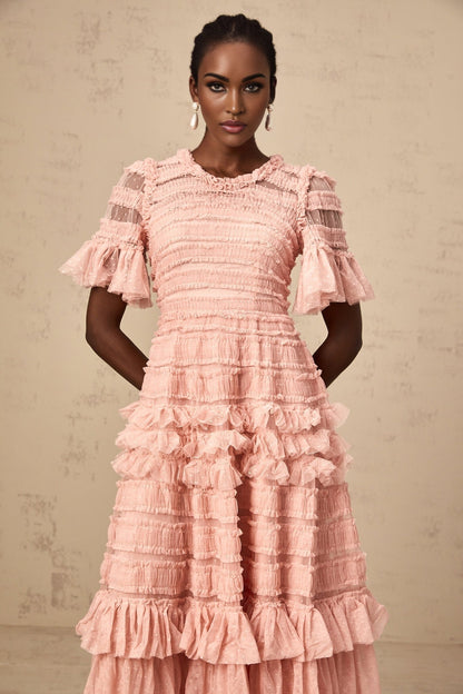 A pink midi dress with a ruffled tulle skirt and small dot details throughout featuring a fitted bodice and delicate shoulder straps