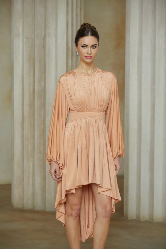 A pink midi dress with an asymmetrical hemline and pleated details featuring a sleeveless design and fitted silhouette