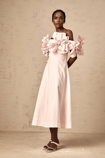 A pink midi dress with an offshoulder neckline featuring three dimensional petal details throughout the garment named Juliette