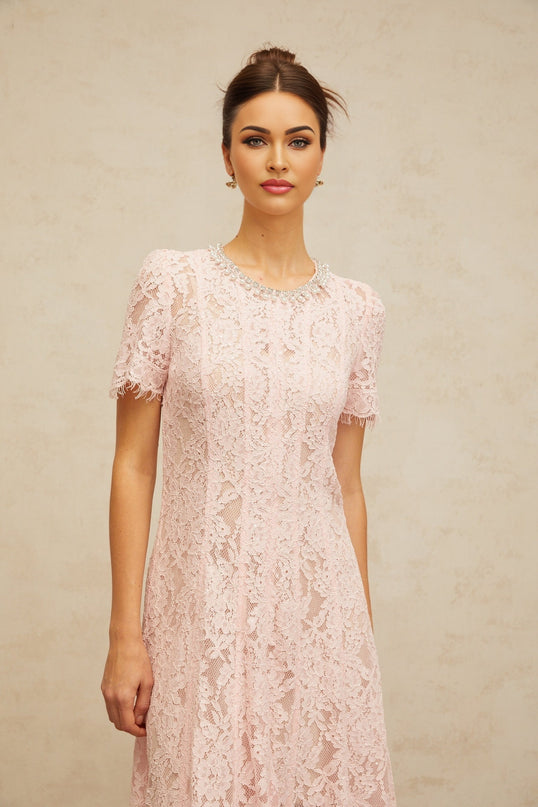 A pink midi dress with floral lace pattern and embellishments on a mannequin or model