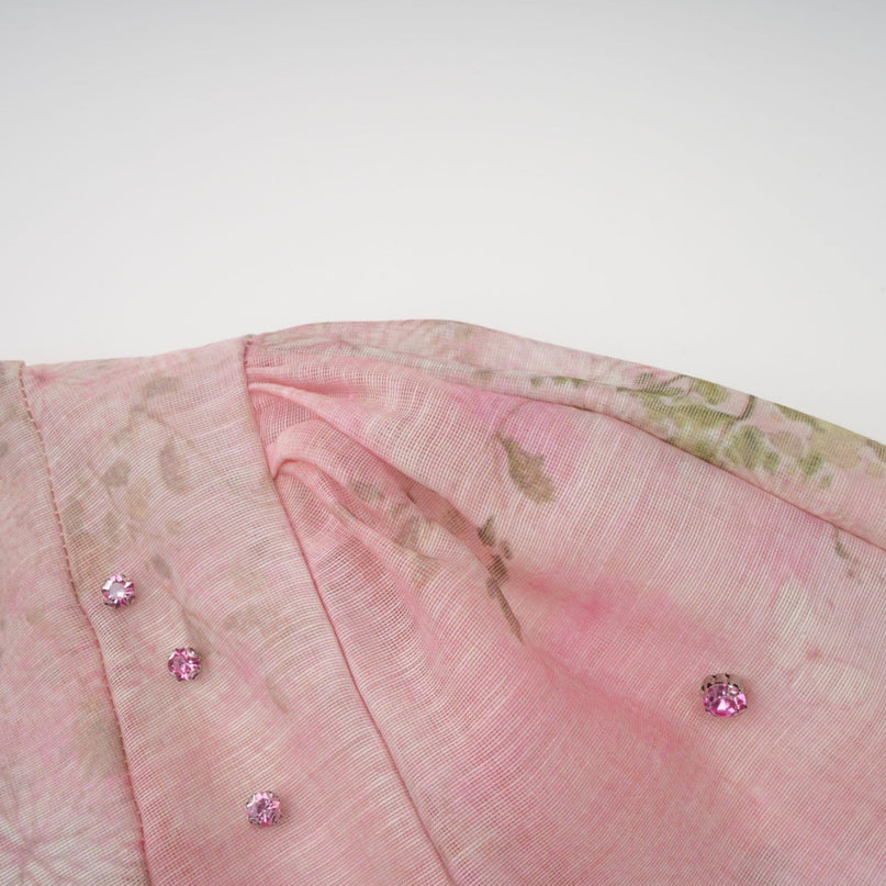 A pink midi dress with floral print and embellishments featuring a design inspired by narcissus flowers