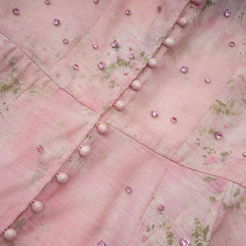 A pink midi dress with floral print pattern and embellished details featuring a design inspired by narcissus flowers