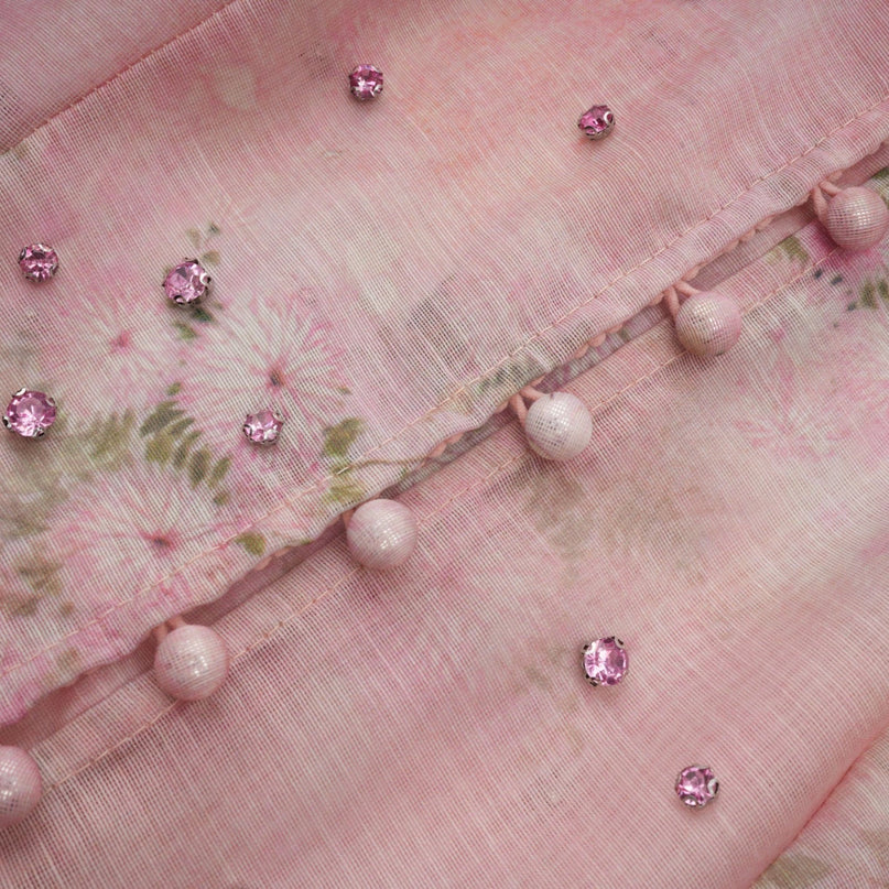 A pink midi dress with floral print pattern and embellishments featuring a design inspired by narcissus flowers