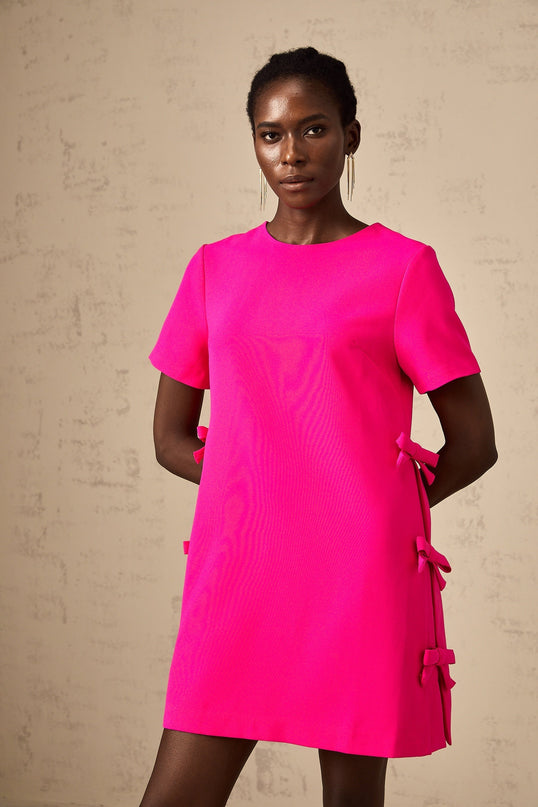 A pink mini dress with a bow detail featuring a feminine and playful design