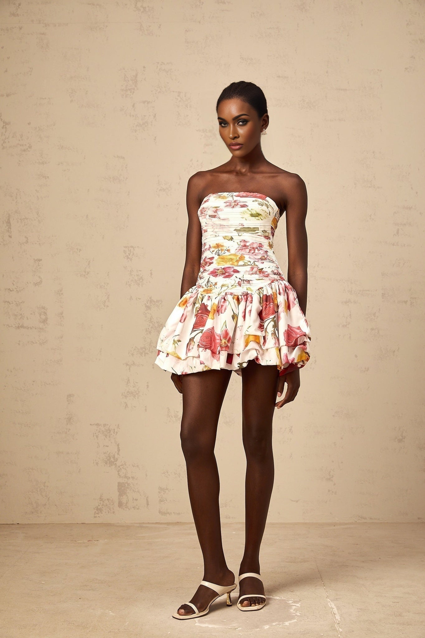 A pink mini dress with a floral print pattern and smocked detailing named Ines