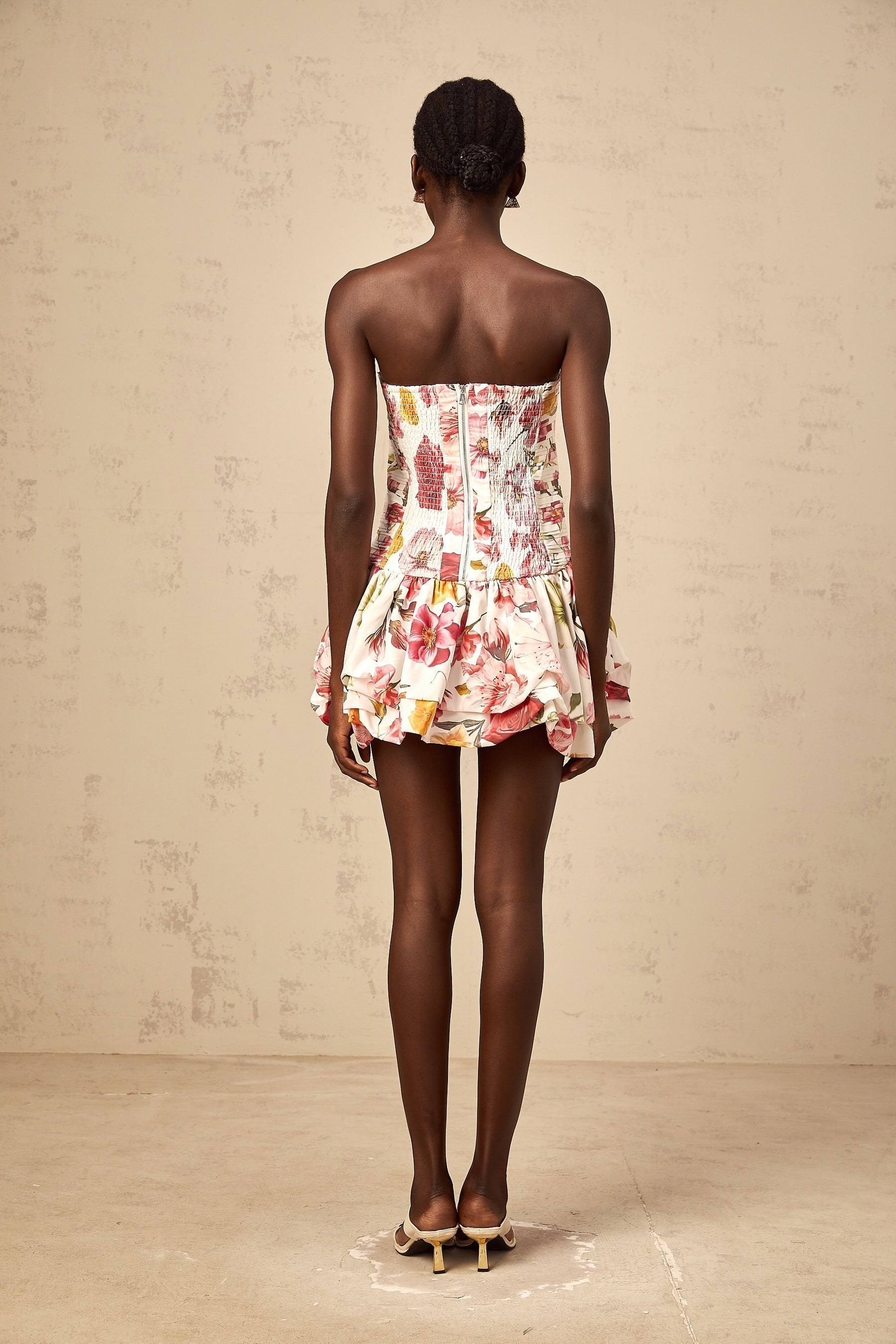A pink mini dress with a floral print pattern and smocked details featuring a design by Ines