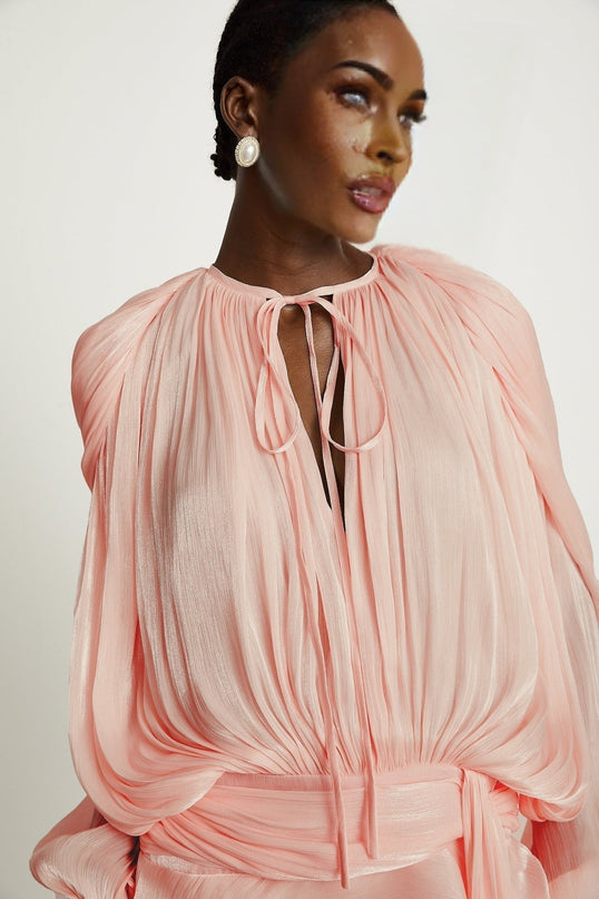 A pink mini dress with full pleats and ruffles called the Eugenie featuring a short hemline and feminine details