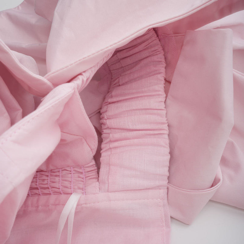 A pink off shoulder midi dress with 3D petal details named Juliette worn by a model against a plain background