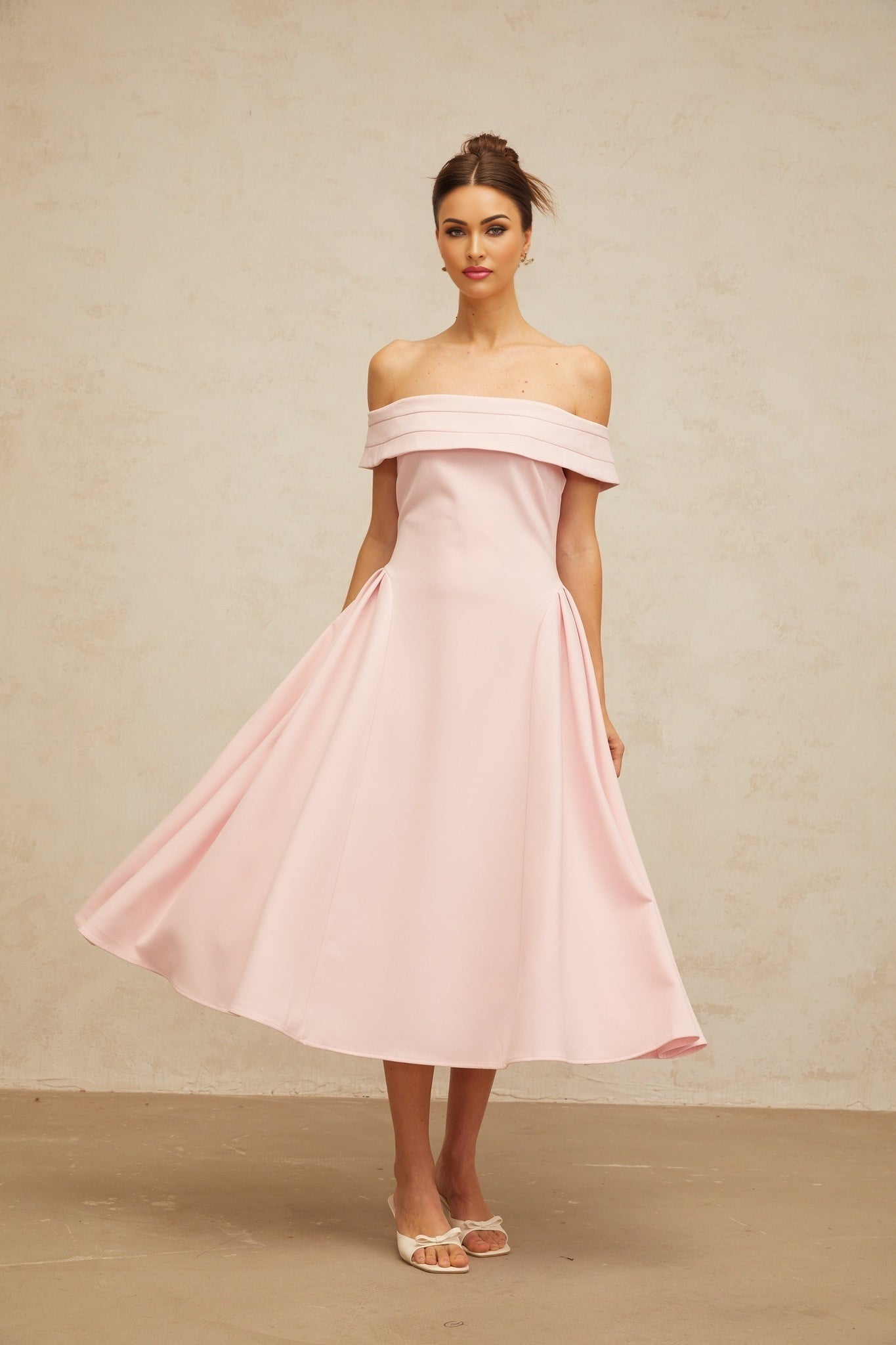 A pink off shoulder midi dress with pleated details and a flowy skirt