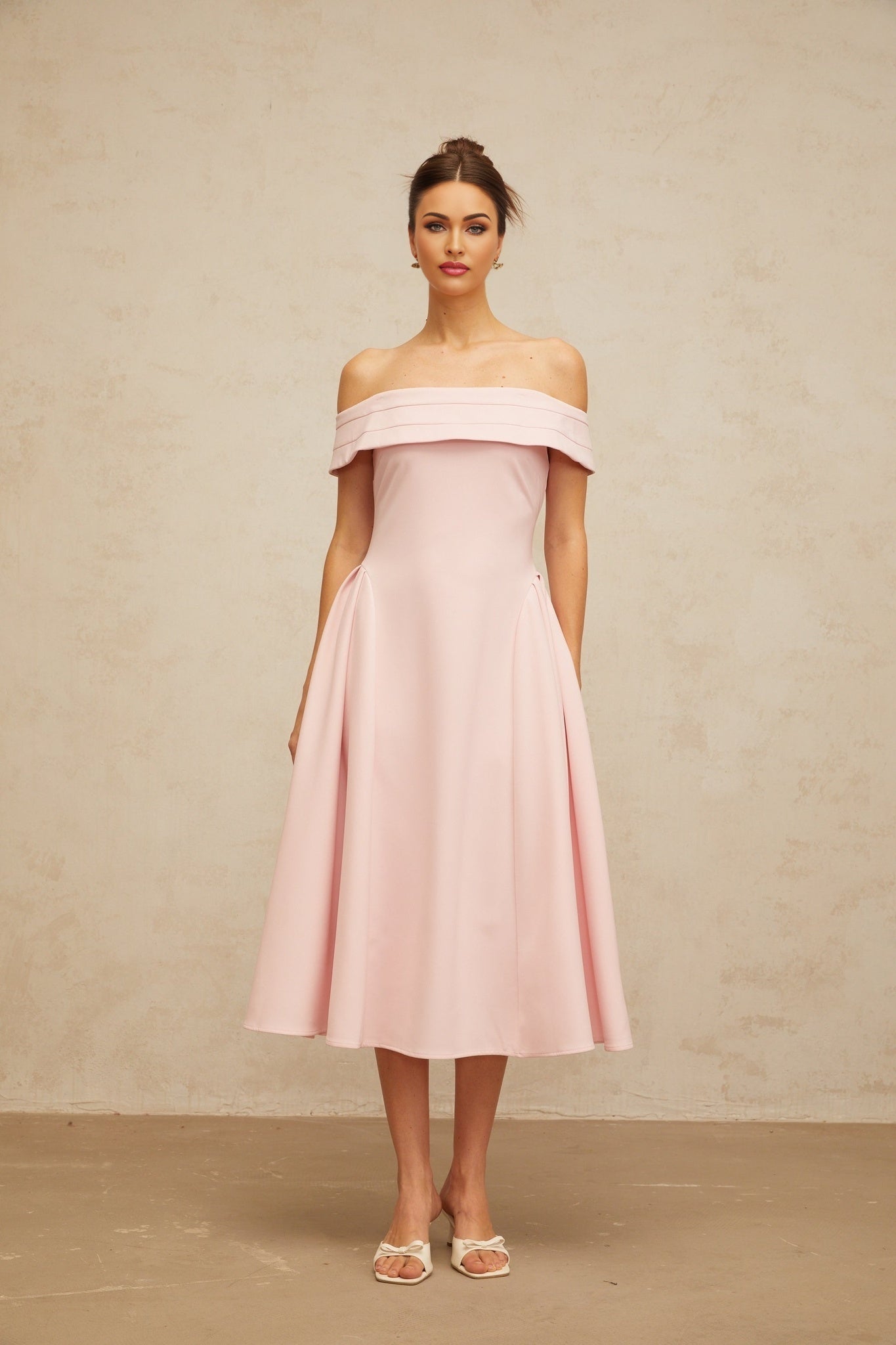 A pink off shoulder midi dress with pleated details featuring a fitted bodice and flowy skirt