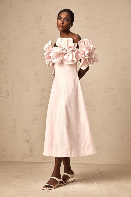 A pink offshoulder midi dress with 3D petal details named Juliette worn by a model against a plain background