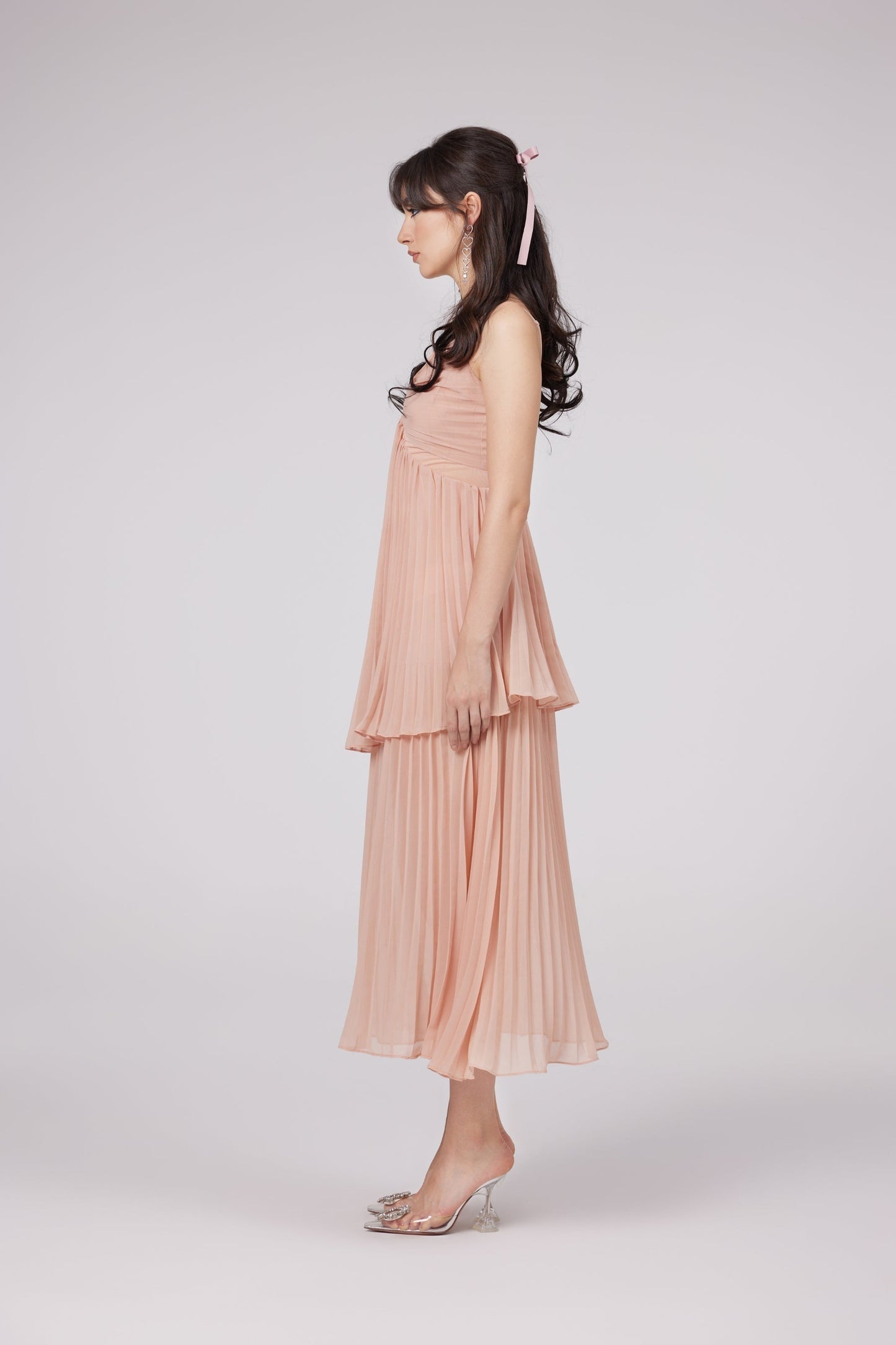 A pink pleated tiered midi dress with the name Olympe featuring a feminine silhouette and flowy layers