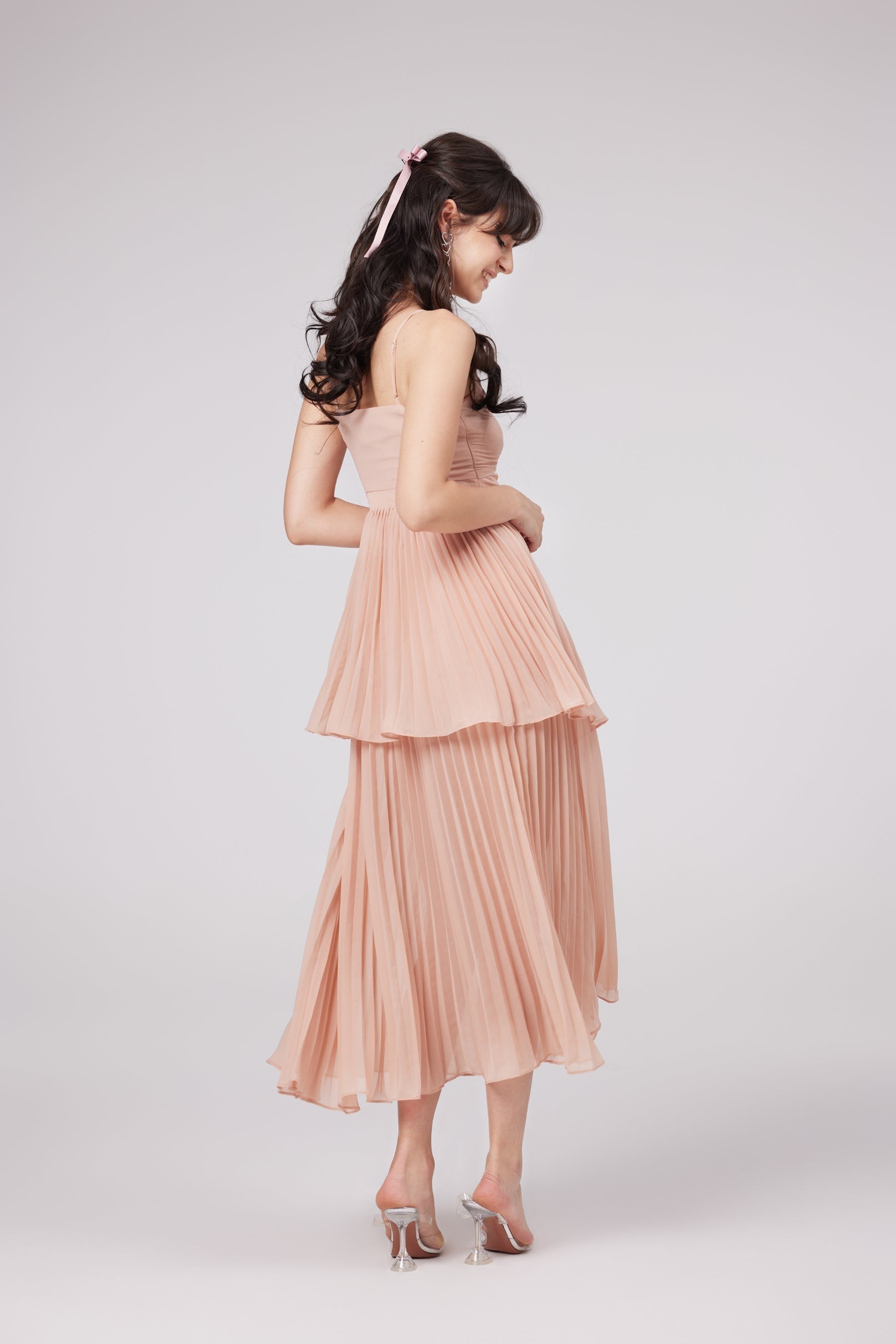 A pink pleated tiered midi dress with the name Olympe