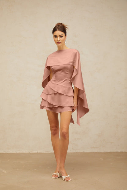 A pink satin mini dress with ruffled details and a shawl panel draping over the shoulders