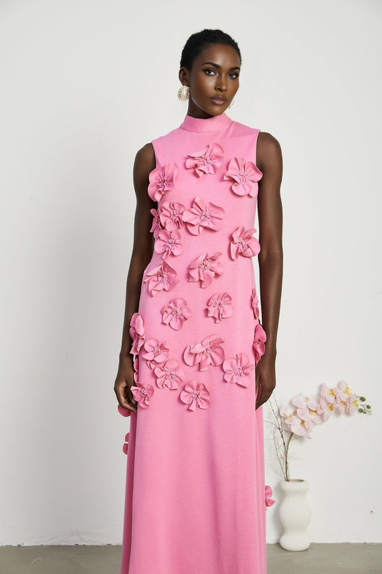 A pink sleeveless maxi dress with a bow and decorative artificial flowers named Magali