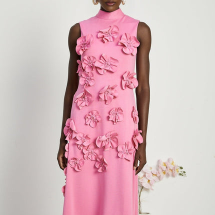 A pink sleeveless maxi dress with a bow and decorative artificial flowers