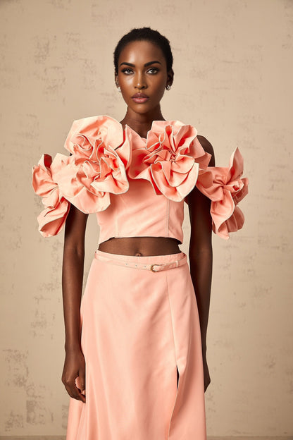 A pink twopiece outfit featuring a top and skirt with floral applique details matching set by Yvette