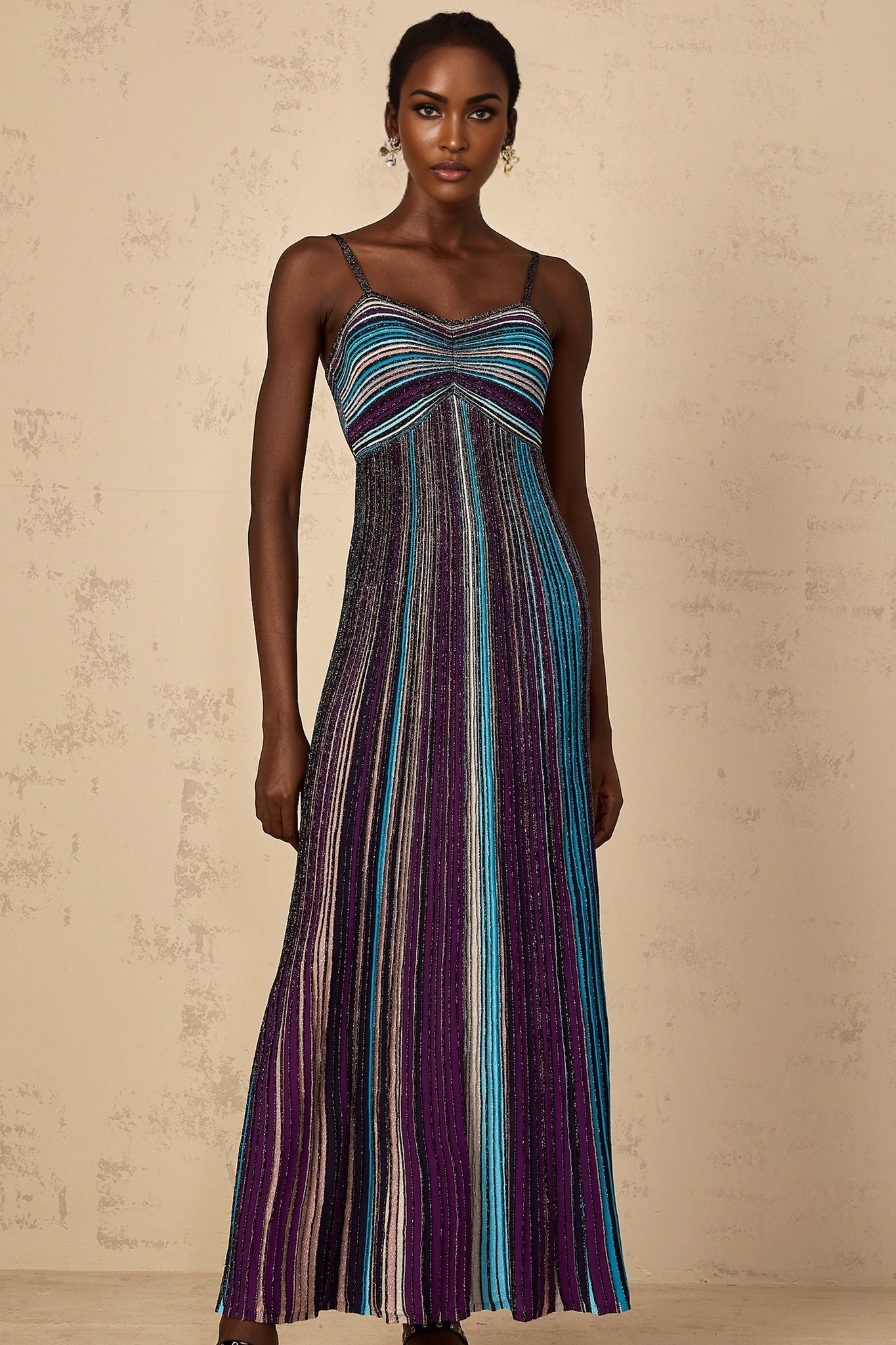 A purple maxi dress with sequin striped pattern on knit fabric worn by a woman standing in a relaxed pose