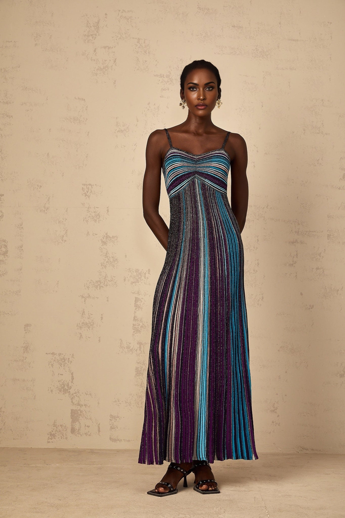 A purple maxi dress with sequin stripes on a knit fabric worn by a woman standing in a neutral pose